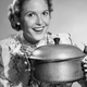 1950s housewife gleefully holds up Dutch oven